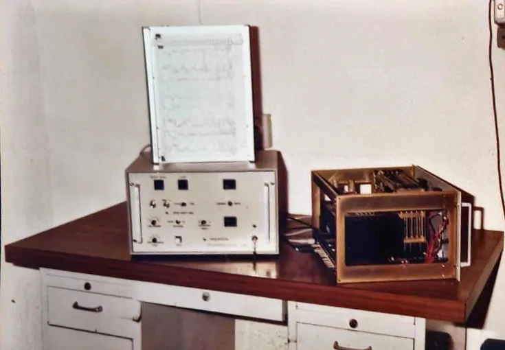 An early ETEP instrument on a desk, with a paper trace on top, next to an open card chassis